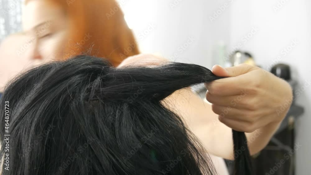 Woman hairdresser stylist makes hairstyle. Special varnish for fixing hair in a spray bottle. Beauty and fashion concept. Black hair.
