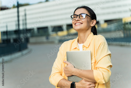 Success. Waist up portrait view of the overjoyed woman embracing her laptop while rejoicing at the street during the sunny day. Stock photo