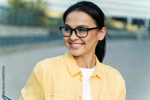 Portrait of the brunette purposeful woman wearing glasses looking away while spending time at the street before her work. Stock photo