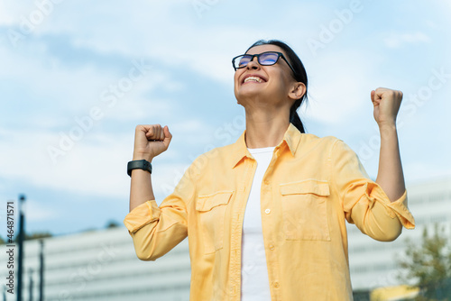 Happy carefree emotions. Energetic joyful adorable woman raising hands and screaming with happiness, while rejoicing victory photo