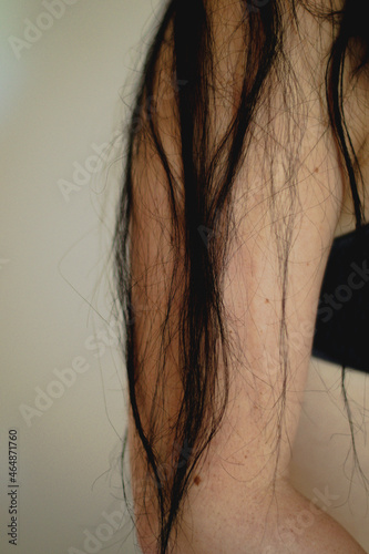 Mano y partes de la piel de una mujer junto con su pelo negro y lunares. photo