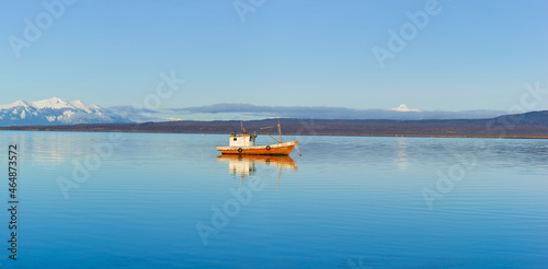 Fjord with small fishing boat and snow covered mountains in south Chile 