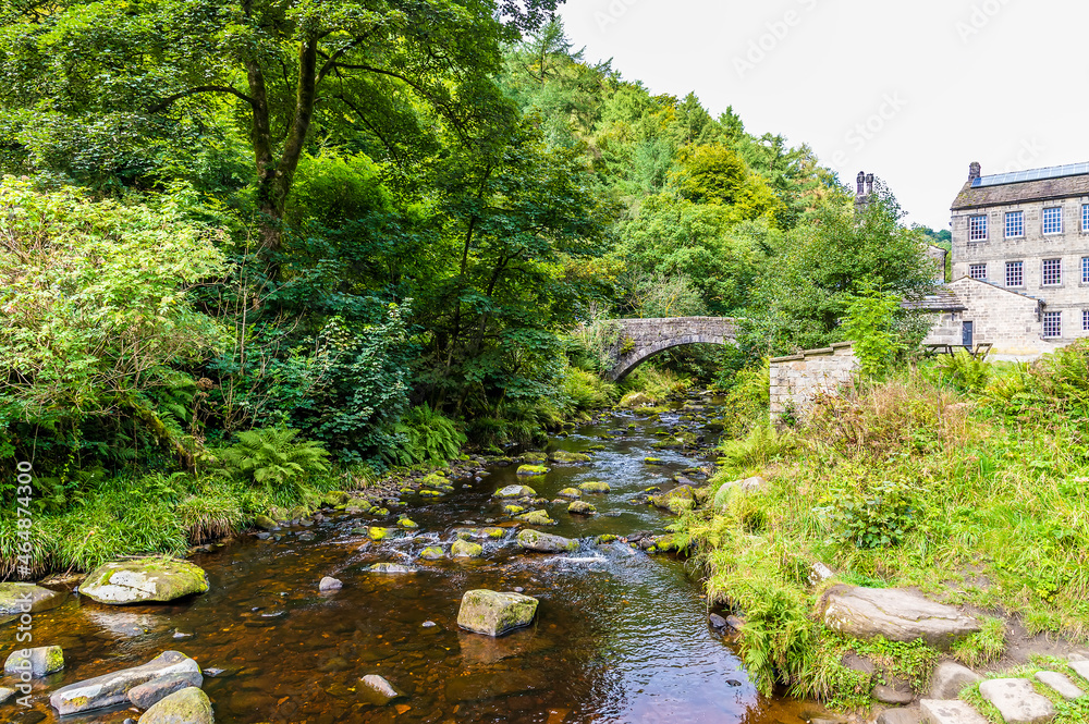A view along Hebden Beck towards a bridge and old mill on the outskirts of Hebden Bridge, Yorkshire, UK in summertime A view along Hebden Beck towards a bridge and old mill on the outskirts of Hebden Bridge, Yorkshire, UK in summertime