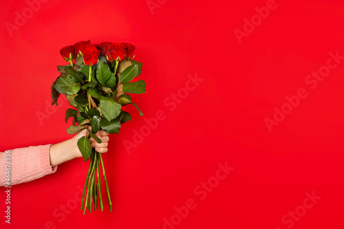 Fototapeta Naklejka Na Ścianę i Meble -  Beautiful bouquet of red roses in a woman hand isolated on white background. Trendy poster for Valentines Day, International Womens Day or mothers day. Banner with Copy space