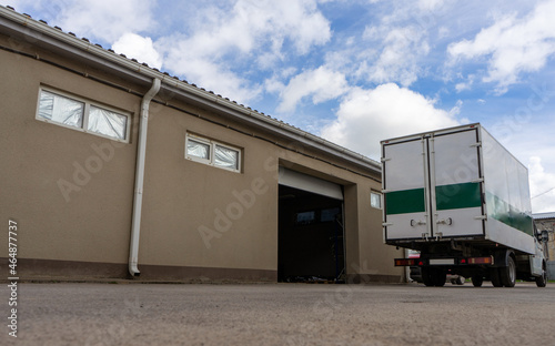 A truck drove up to a building with an open gate for loading and transporting cargo. Production logistics.