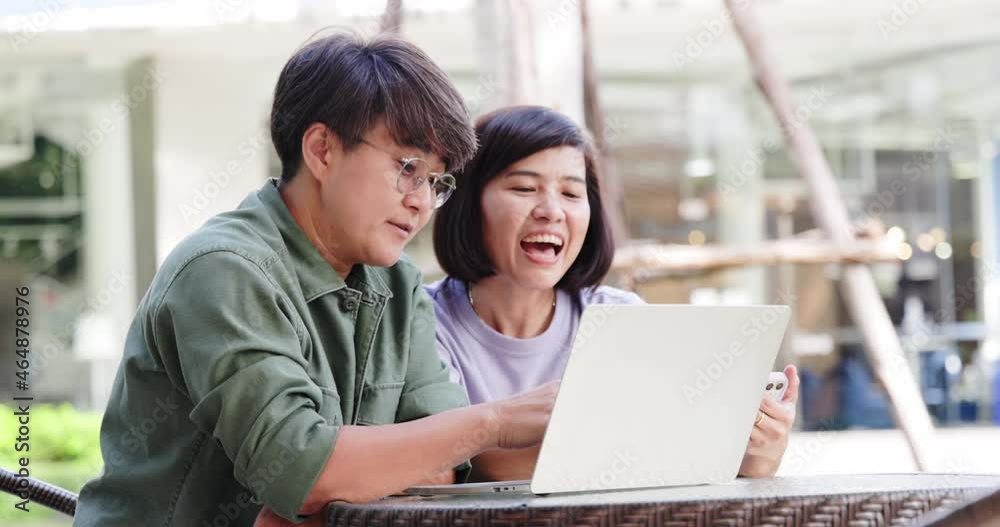 Asian couple two women using laptop and smartphone for online business working success and happy. Shopping online using high speed free wifi 5g work at coffee shop. Successful bond money investment Asian couple two women using laptop and smartphone for online business working success and happy. Shopping online using high speed free wifi 5g work at coffee shop. Successful bond money investment