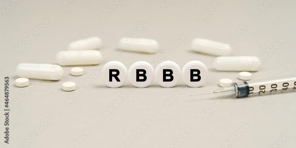 On the table are capsules, a syringe and pills that say - RBBB On the table are capsules, a syringe and pills that say - RBBB