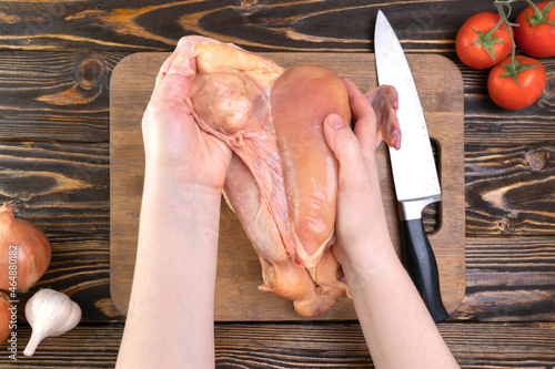 The chef's hands peel off the skin from the chicken breast. Chicken fillet