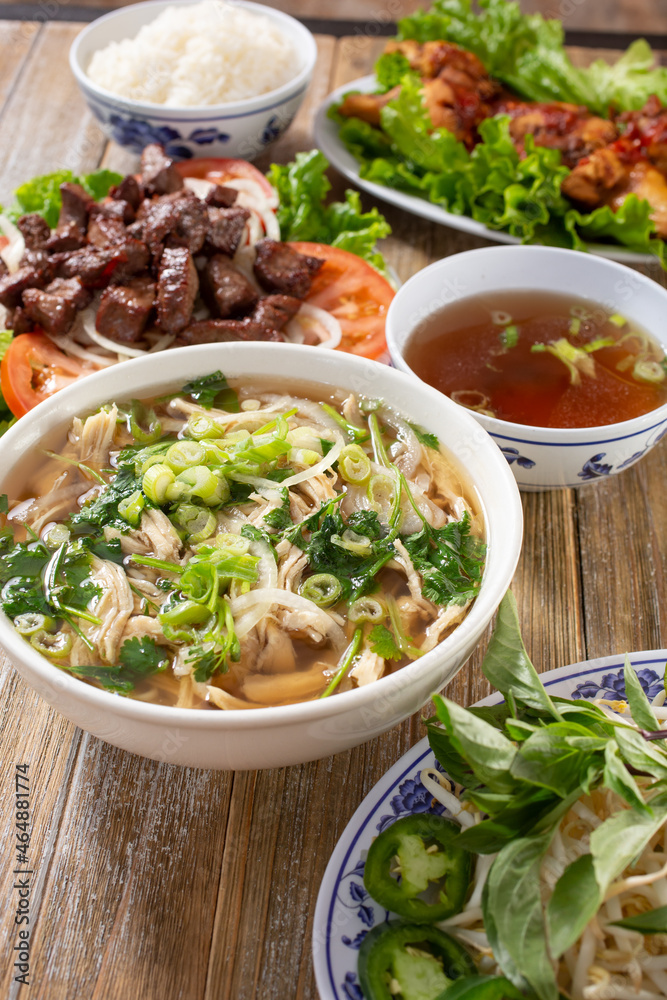 A view of an array of Vietnamese entree, featuring pho, shaking beef, and chicken wings. A view of an array of Vietnamese entree, featuring pho, shaking beef, and chicken wings.