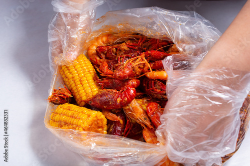 A view of hands opening a plastic bag full of seafood boil, at a local restaurant. photo