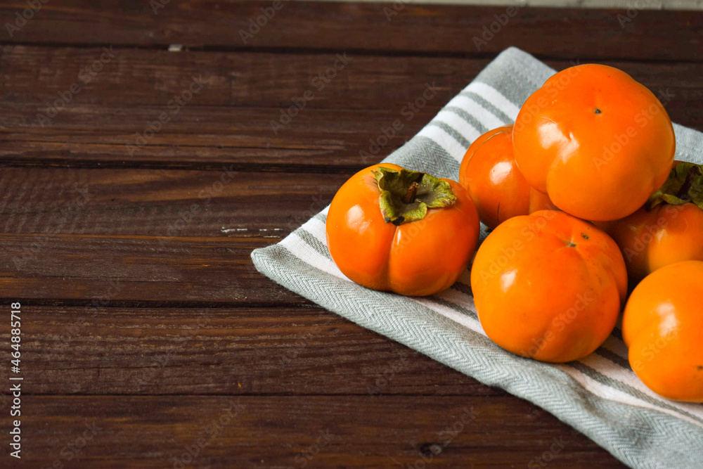 orange persimmon lies on a wooden background. still-life orange persimmon lies on a wooden background. still-life