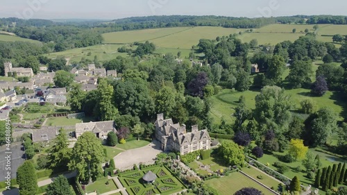 Aerial showing green fields, hills and gardens of English countryside between upper and lower slaughter in Cheltenham, Cotswold England, UK