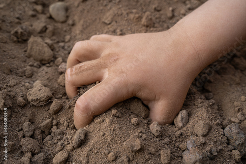 Children's hand digs in brown earth 