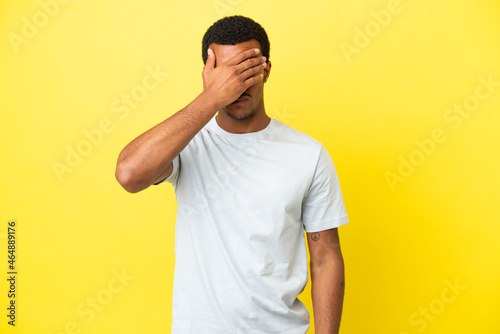 African American handsome man on isolated yellow background with headache
