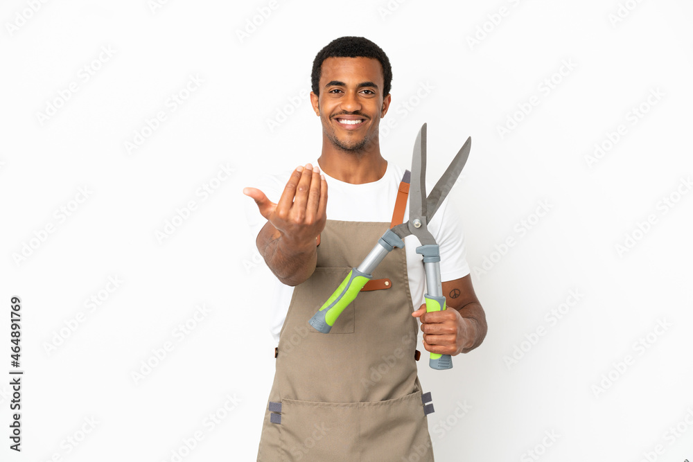 African American gardener man holding pruning shears over isolated white background inviting to come with hand. Happy that you came African American gardener man holding pruning shears over isolated white background inviting to come with hand. Happy that you came