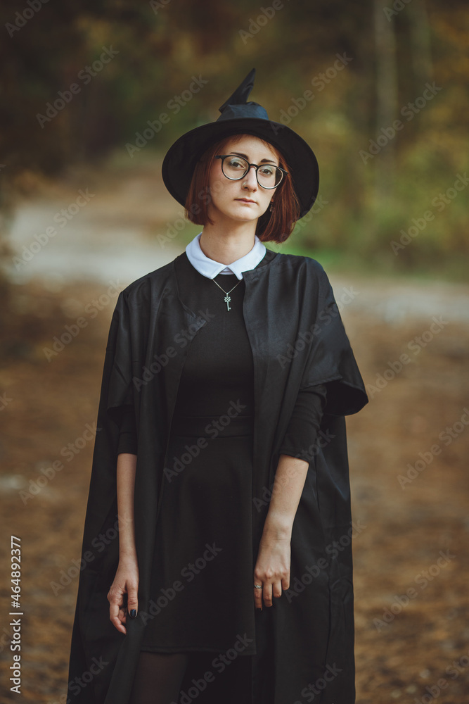 Halloween Witch. Portrait of a girl in a hat and a witch costume in the forest. Ready for trick or treat holiday