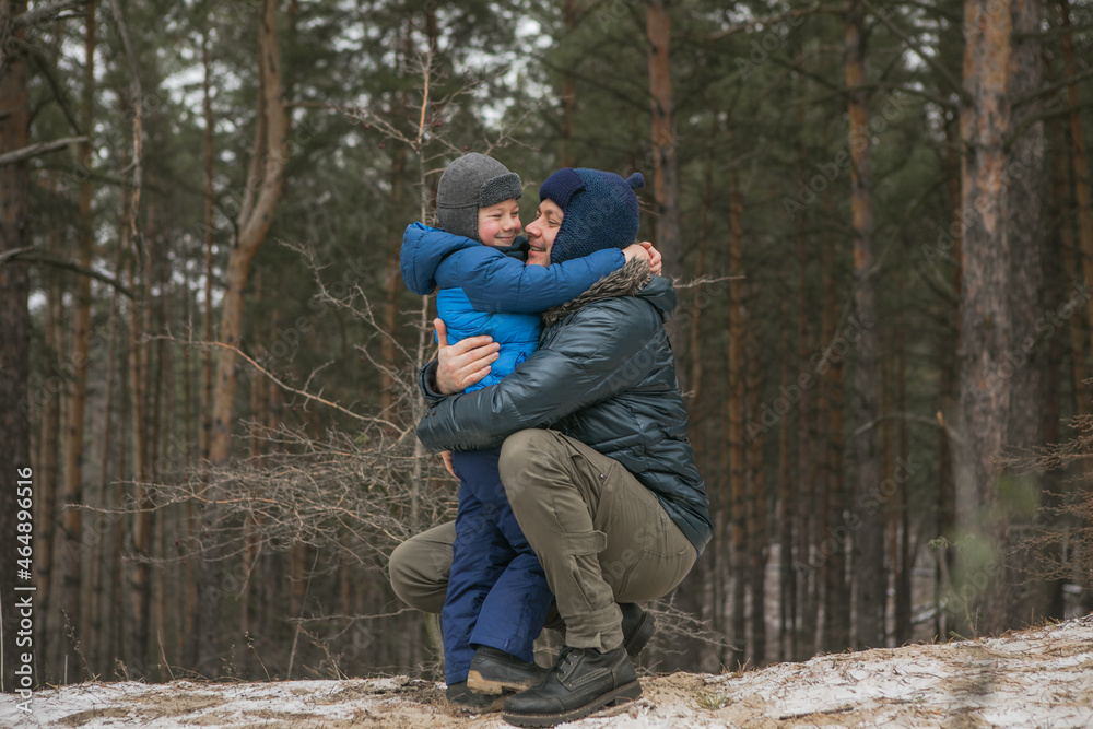 Happy family on a walk outdoors in sunny winter forest, Christmas holidays, father and son play together