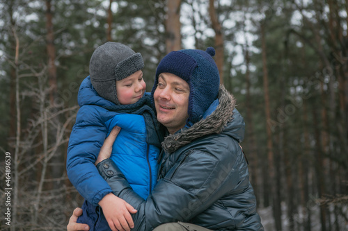 Happy family on a walk outdoors in sunny winter forest  Christmas holidays  father and son play together