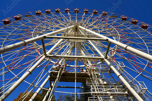 Photo of a ferris wheel in a park in the city on the background of blue clear sky