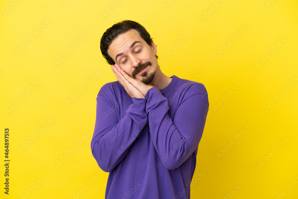 Young caucasian man isolated on yellow background making sleep gesture in dorable expression Young caucasian man isolated on yellow background making sleep gesture in dorable expression