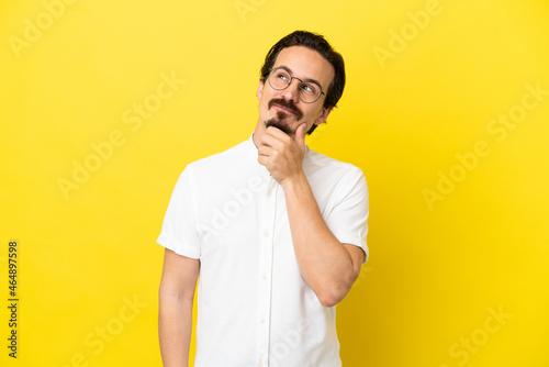 Young caucasian man isolated on yellow background and looking up