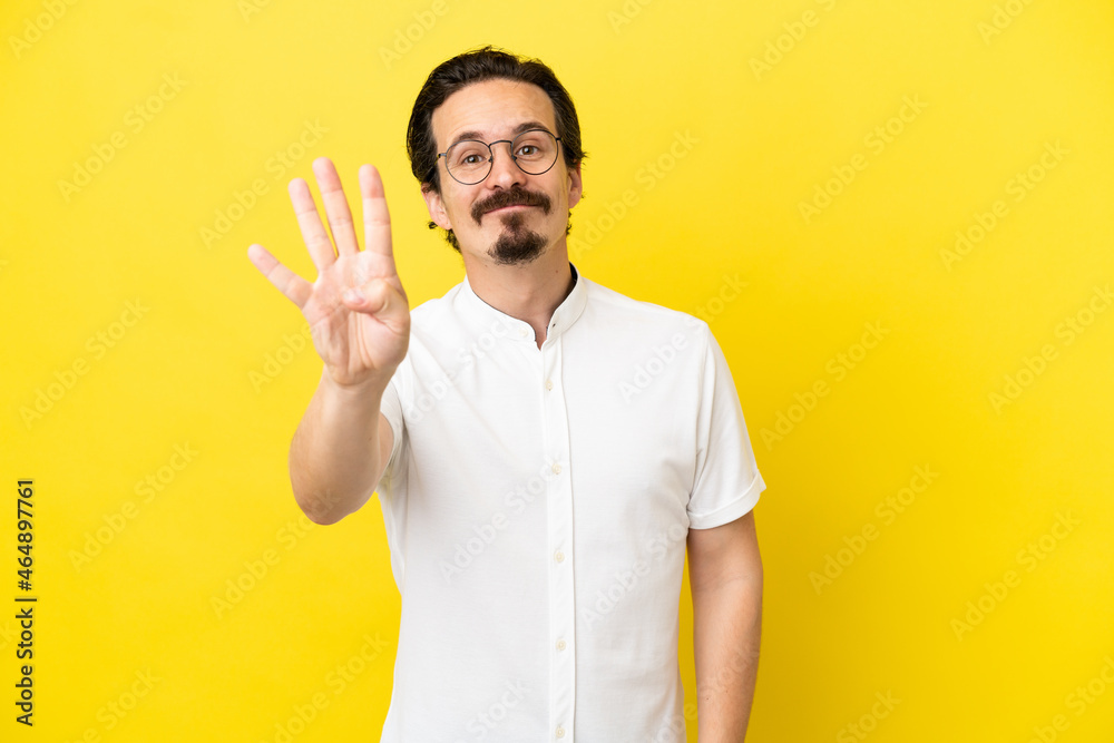 Young caucasian man isolated on yellow background happy and counting four with fingers Young caucasian man isolated on yellow background happy and counting four with fingers