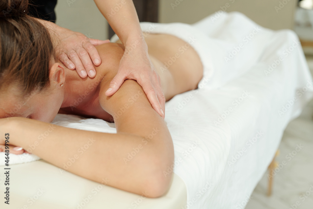 Young relaxed woman lying on massage table during bodycare procedure in luxurious spa salon Young relaxed woman lying on massage table during bodycare procedure in luxurious spa salon