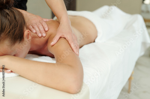 Young relaxed woman lying on massage table during bodycare procedure in luxurious spa salon