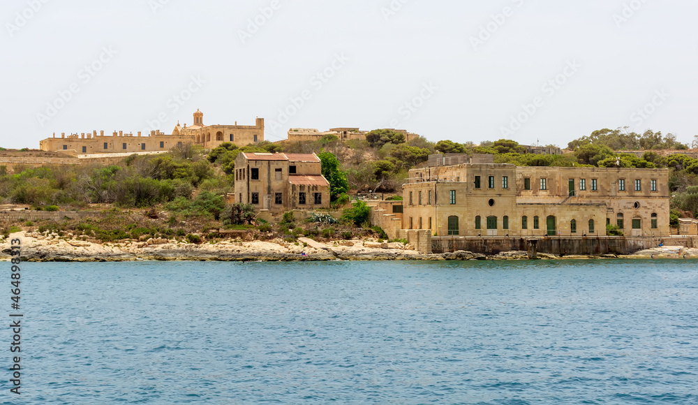 Old ruined buildings at  Manoel Island in Gzira, Malta, with fort Manoel walls in the background.