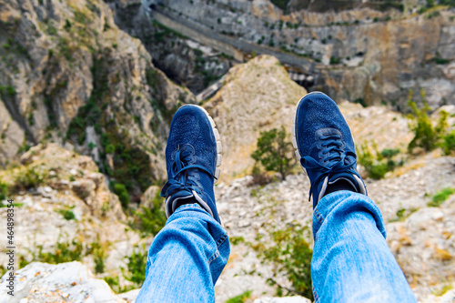 A selfie of men's feet in sneakers on a hilltop enjoying the view