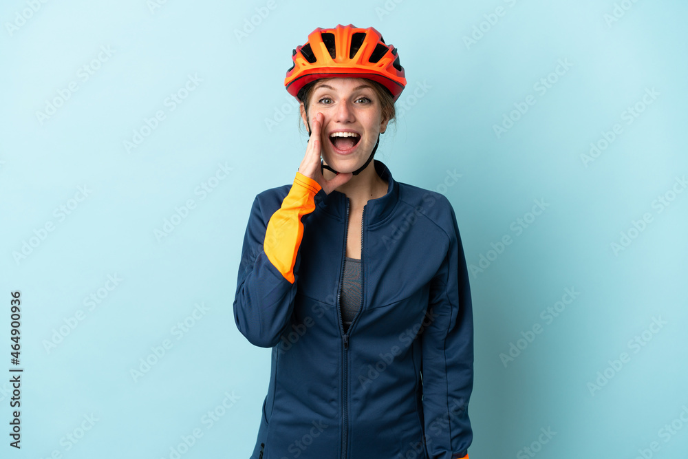 Young cyclist woman isolated on blue background with surprise and shocked facial expression - obrazy, fototapety, plakaty 