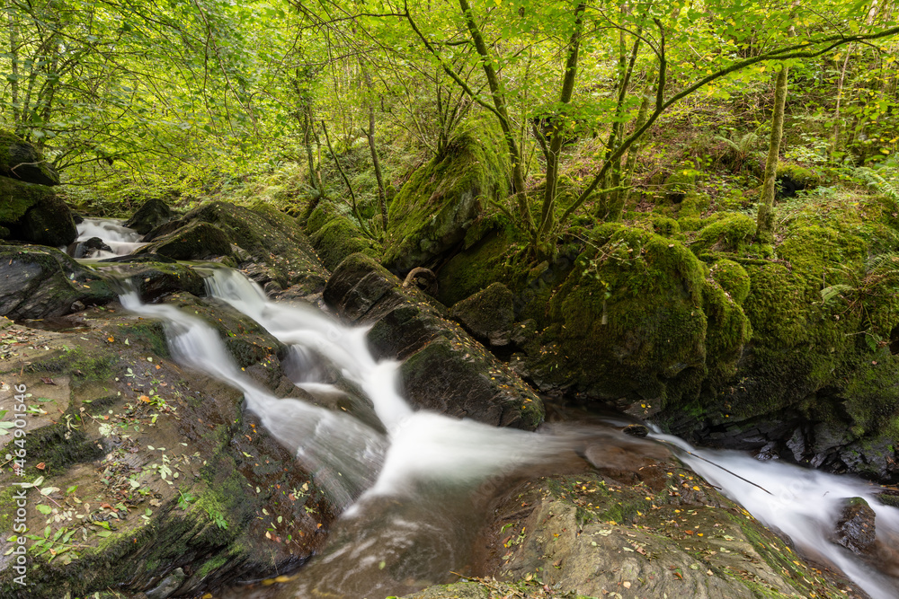Long exposure of a waterfall on the Hoar Oak Water river flowing through the woods at Watersmeet in Exmoor National Park Long exposure of a waterfall on the Hoar Oak Water river flowing through the woods at Watersmeet in Exmoor National Park