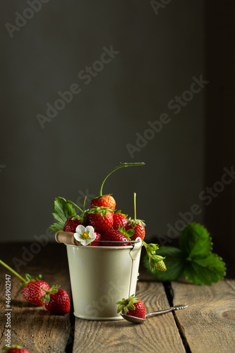 juicy red strawberries in a mini bucket on a wooden background. High quality photo