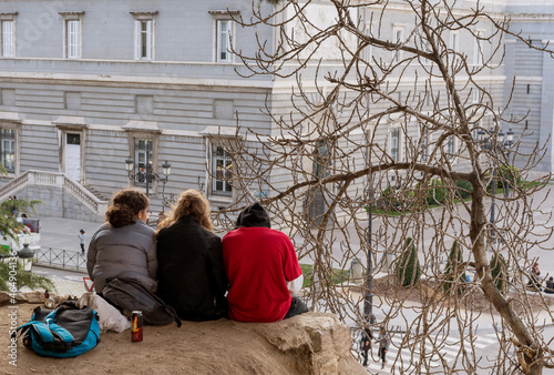 three girls sit on the ground in front of a historic building in Madrid