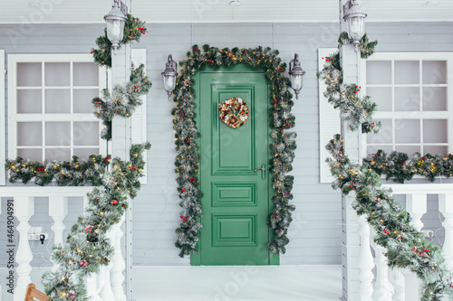 Green door entrance to the house. Christmas festive deco decorated with Christmas tree branches