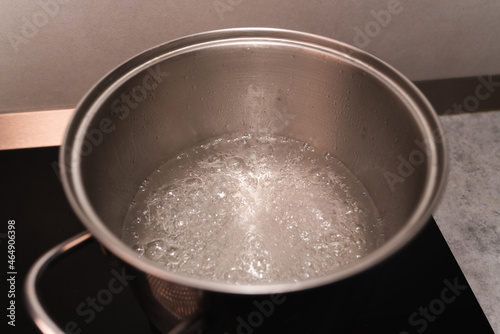 Boiling water in a metal saucepan on the black surface of an induction cooker