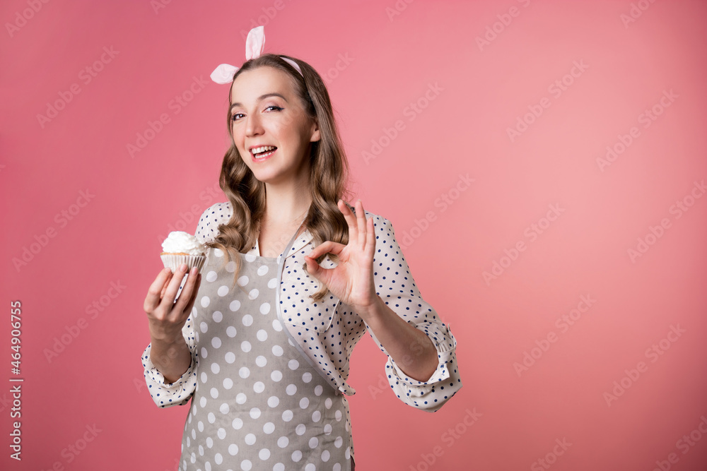 Young charming woman pastry chef and delicious muffin with cream. A cook in a polka-dot apron.