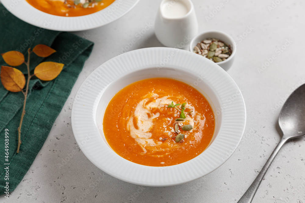 pumpkin soup with seeds and cream in a white plate on a gray table pumpkin soup with seeds and cream in a white plate on a gray table