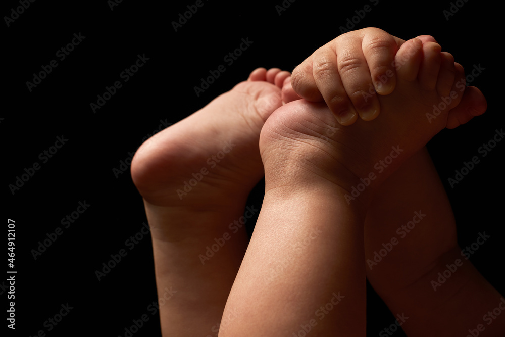 Close up newborn fingers feet and hands isolated on black background 