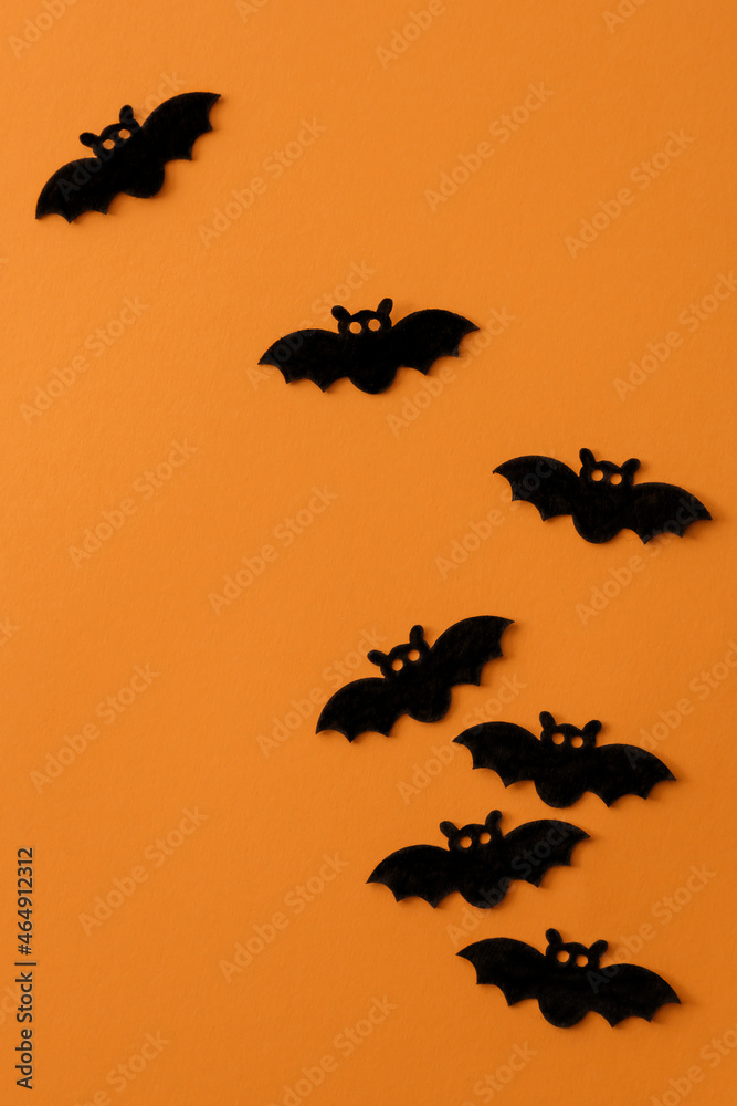 Group of bats against orange background. Flat spooky Halloween composition.