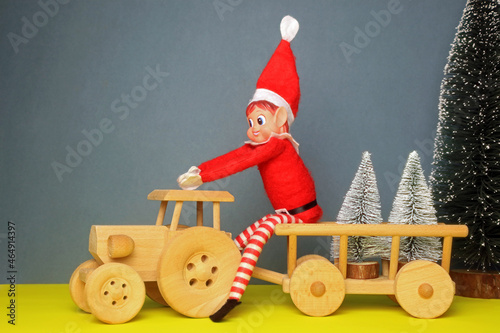 Photos Christmas elf sitting on a wooden tractor and trailing transporting fir trees