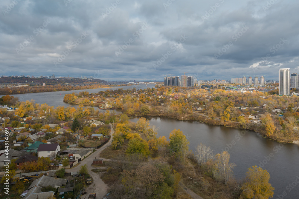 Beautiful panorama of autumn Kiev. View from the left bank to the Dnieper. Wide river in the city and autumn yellow trees.Village and city