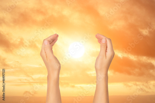 Open palms holding sun on background of sunset sky. Travel and inspiration  meditation concept.