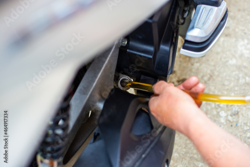 A car mechanic pours engine oil through a tube into a motorbike engine. Motorcycle oil change