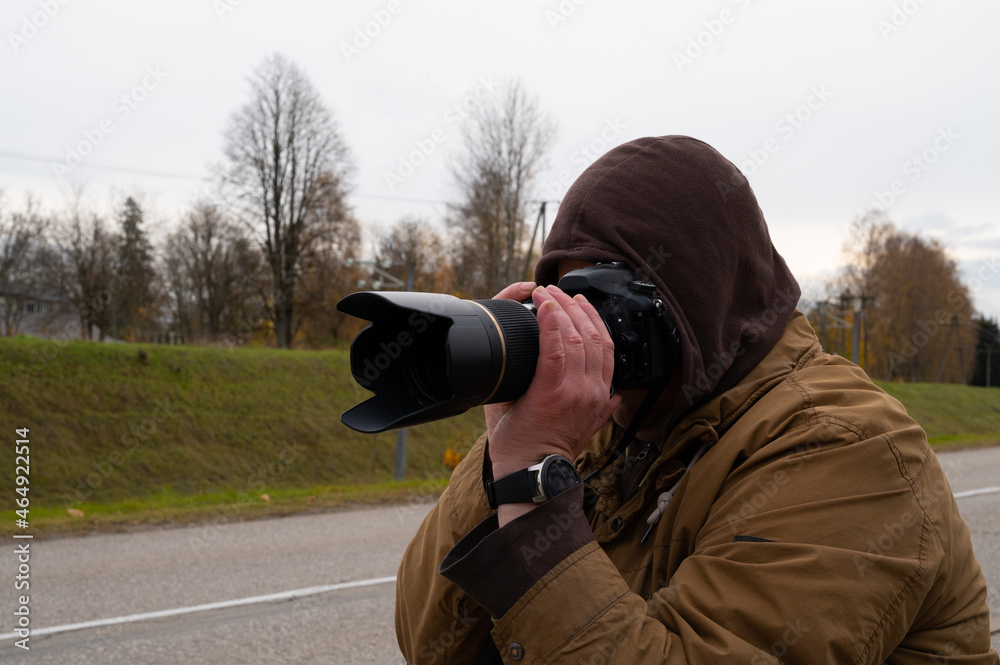 Close-up of a photographer shooting a city view in the cold autumn weather.