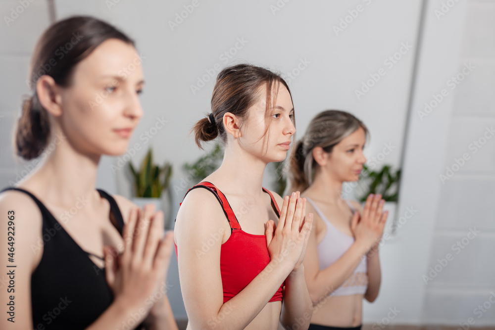 Three girls practicing yoga. Yoga instructor with her students meditating in a studio. Three girls practicing yoga. Yoga instructor with her students meditating in a studio.