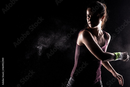 Kickboxer kirl with magnesium powder on her hands, punching with dust visible.