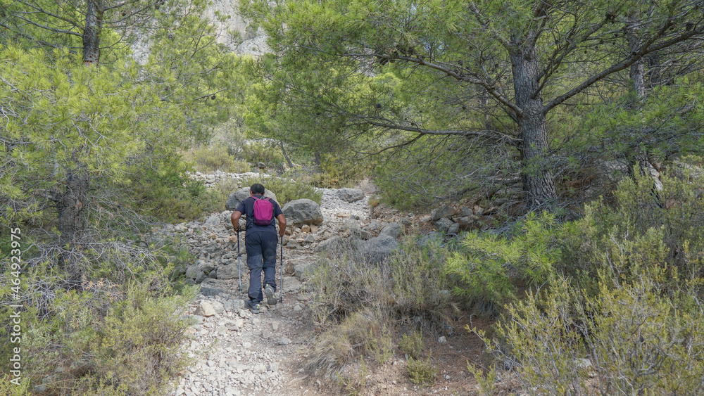 Senderista subiendo a una montaña por una senda de montaña mediterránea