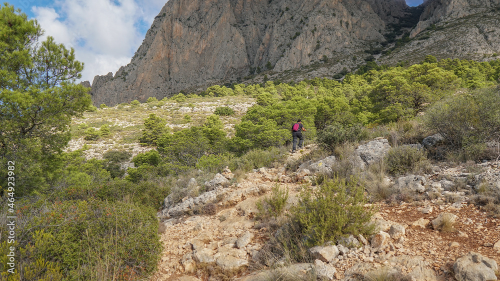 Senderista subiendo a una montaña por una senda de montaña mediterránea