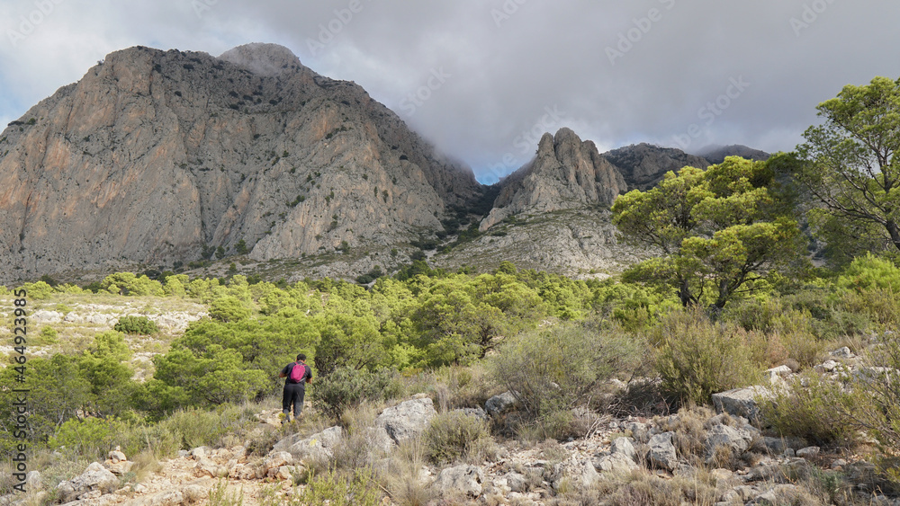 Senderista subiendo a una montaña por una senda de montaña mediterránea